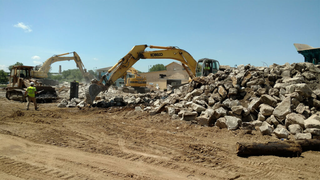Excavators piling demolished concrete at a construction site